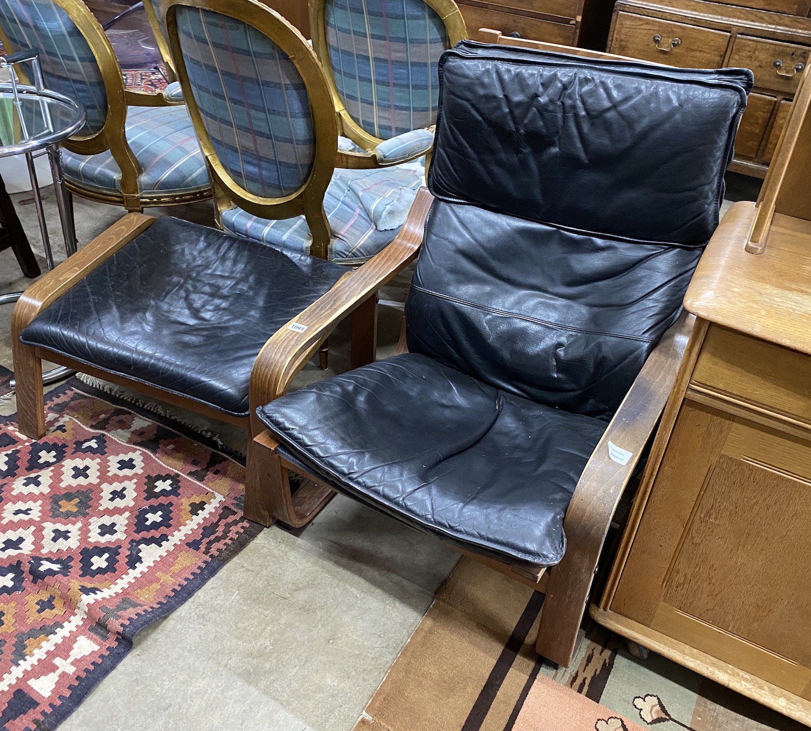 A 1970's beech and black leather reclining armchair, width 68cm, depth 72cm, height 93cm and matching stool